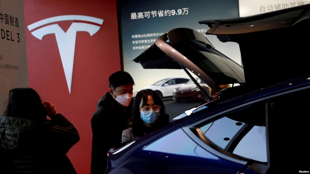 FILE - Visitors wearing face masks check a China-made Tesla Model Y sport utility vehicle (SUV) at the electric vehicle maker's showroom in Beijing, China, Jan. 5, 2021.