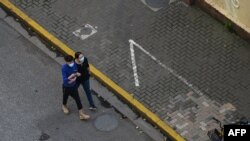 FILE - People walk on a street during a Covid-19 coronavirus lockdown in the Jing'an district, in Shanghai on May 21, 2022. 