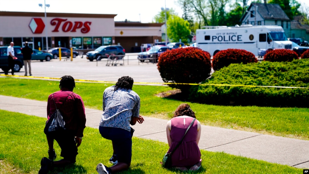 People pray outside the scene of a shooting at a supermarket, in Buffalo, NY, May 15, 2022.