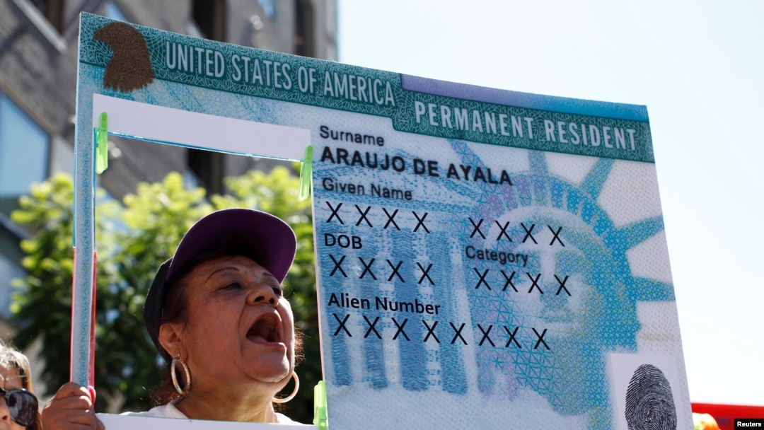 FILE - A woman holds an enlarged replica of a green card during a rally to demand immigration reform, in Los Angeles, Oct. 5, 2013.