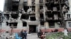 Los residentes se reúnen frente a un edificio residencial gravemente dañado durante la invasión rusa de Ucrania, en la ciudad portuaria sureña de Mariupol, el 21 de abril de 2022.