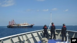 2021 年 4 月 27 日，菲律賓海岸警衛隊提供的照片中，其人員在南海薩賓娜淺灘的據稱是中國民兵船的船隻旁邊巡邏。菲律賓政府抗議中國海警...
