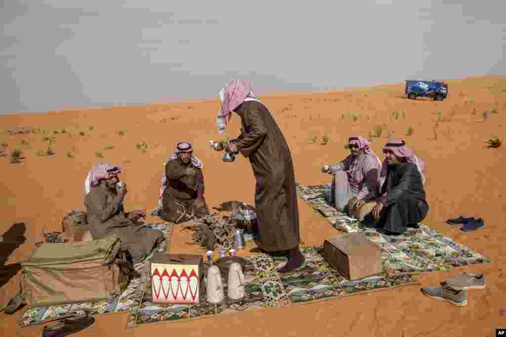 Local spectators drink tea and coffee on the dunes during stage six of the Dakar Rally between Hail and Riyadh, Saudi Arabia.