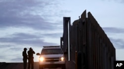 FILE - In this Nov. 21, 2018, photo, U.S. Border Patrol agents stand by a vehicle near one of the border walls separating Tijuana, Mexico, and San Diego, in San Diego.