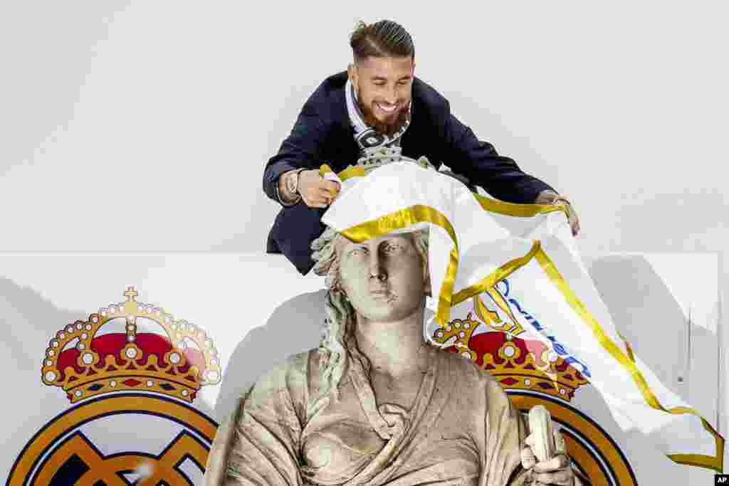 Player Sergio Ramos ties a Real Madrid flag around the neck of goddess Cibeles monument as the team arrives at Cibeles square after winning the Champions League final soccer match between Real Madrid and Atletico Madrid, in Madrid, Spain.
