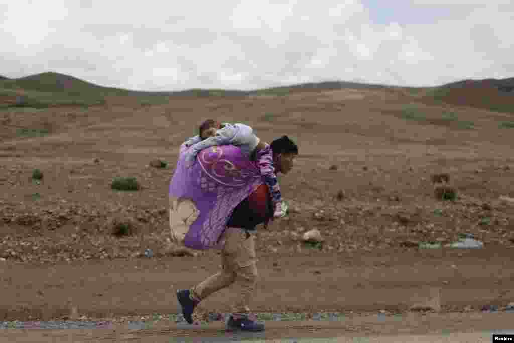 A man carries his daughter as he walks near a road block made by anti-government protesters to demand Peru's President Dina Boluarte to step down, in Condoroma in Cusco region, Feb. 4, 2023.
