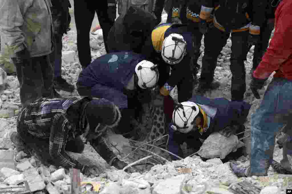 Civil defense workers search through the rubble of collapsed buildings in the Besnia village near the Turkish border, Idlib province, Syria, Feb. 6, 2023.