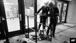 ARCHIVO - Un guardia de seguridad y otra persona no identificada miran el sitio donde varias personas murieron y otras resultaron heridas cuando quedaron atrapados en una multitud que ingresaba al Riverfront Coliseum de Cincinnati para un concierto de The Who el 3 de diciembre de 1979. (Foto AP/Brian Horton, archivo)