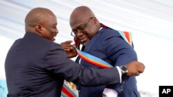 Congolese President Felix Tshisekedi, right, receives the presidential sash from outgoing president Joseph Kabila after being sworn in in Kinshasa, Democratic Republic of the Congo, Thursday Jan. 24, 2019.