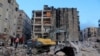 La gente se reúne entre los escombros mientras continúa la búsqueda de sobrevivientes, después del terremoto, en Alepo, Siria, el 7 de febrero de 2023. 