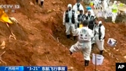 In this image taken from video footage run by China's CCTV, search-and-rescue workers stand at the area where they recovered the second orange-colored "black box" at the China Eastern flight crash site in Tengxian County, March 27, 2022, in southern China