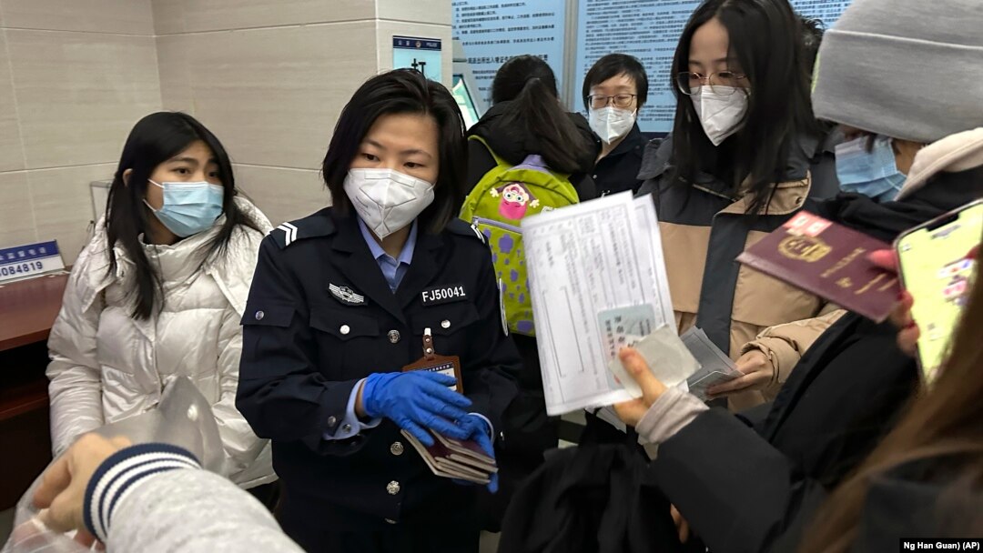 An officer collects passports from residents for renewal and re-applications at a community police station in Beijing, Wednesday, Dec. 28, 2022. (AP Photo/Ng Han Guan)