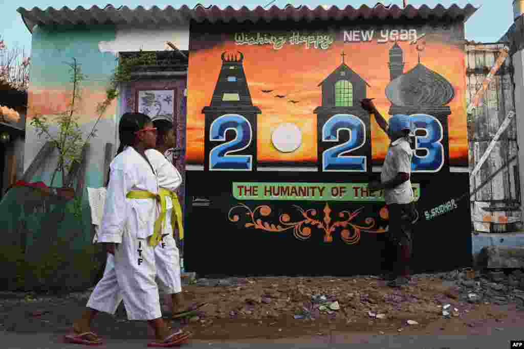 An artist puts finishing touches on a New Year mural painted on his house in Chennai, India.