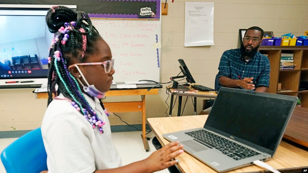 Ryan Johnson, a fifth-grade teacher at Pecan Park Elementary School, right, monitors his daughter Rylei, while she checks her homework schedule before they leave for home in Jackson, Miss., Tuesday, Sept. 6, 2022. (AP Photo/Rogelio V. Solis)