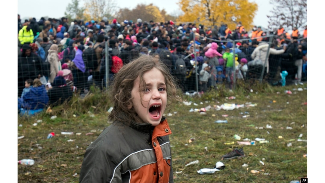 FILE - A girl cries as hundreds of migrants wait to cross into Austria from Sentilj, Slovenia, Oct. 29, 2015.