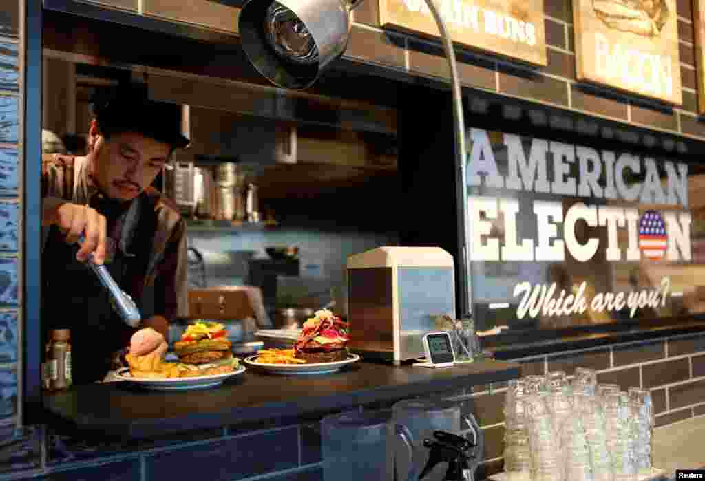 J.S. Burgers Cafe chef Yasuhito Fukui prepares Mr. and Mrs. Burger representing the U.S. presidential candidates Hillary Clinton and Donald Trump, at a hamburger joint in Tokyo, Japan. Clinton's burger includes ingredients that reflect Chicago, while Trump's burger represents New York.