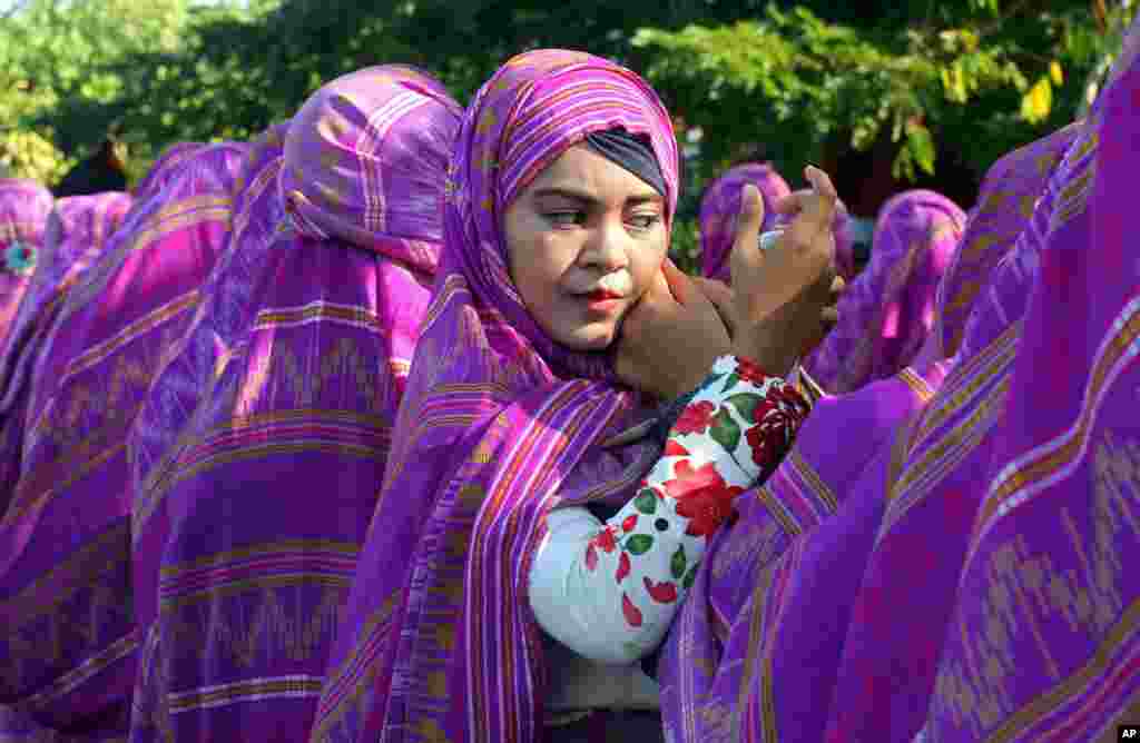 A woman adjusts her headscarf during a cultural and environmental themed parade in Bali, Indonesia.