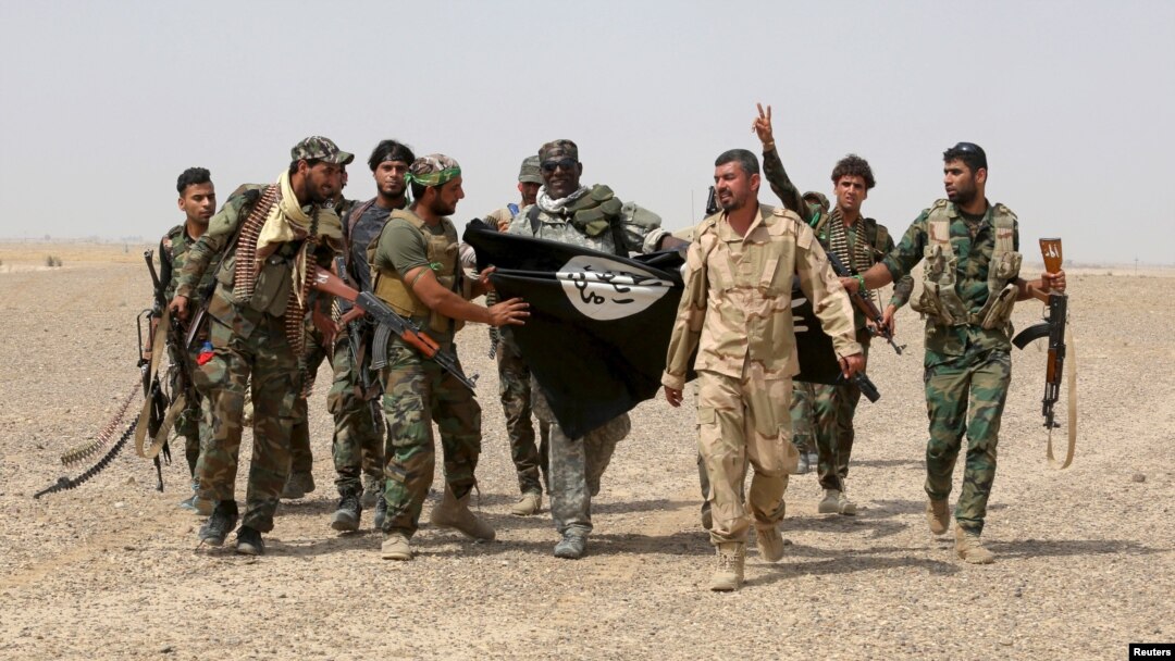 Iraq's Shi'ite paramilitaries and members of Iraqi security forces hold an Islamist State flag which they pulled down in Nibai, in Anbar province, May 26, 2015.