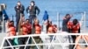 Migrants wave and give the v-sign as they disembark at Hay Wharf, Pieta, Malta, Jan. 9, 2019. 