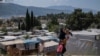 ARHIVA - Avganistanka sa troje dece šeta ispred izbegličkog kampa na ostrvu Samos u Grčkoj, 11. juna 2021. 