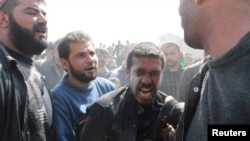 A man mourns relatives who died at a site hit by what activists say was an government air strike in Daiaat Al-Ansari neighborhood in Aleppo Mar. 30, 2013.