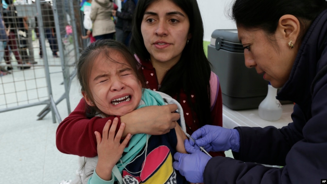 A Venezuelan girl cries while receiving a measles vaccine at an immigration processing office on the Rumichaca bridge, after crossing the border from Colombia to Ecuador, June 13, 2019.