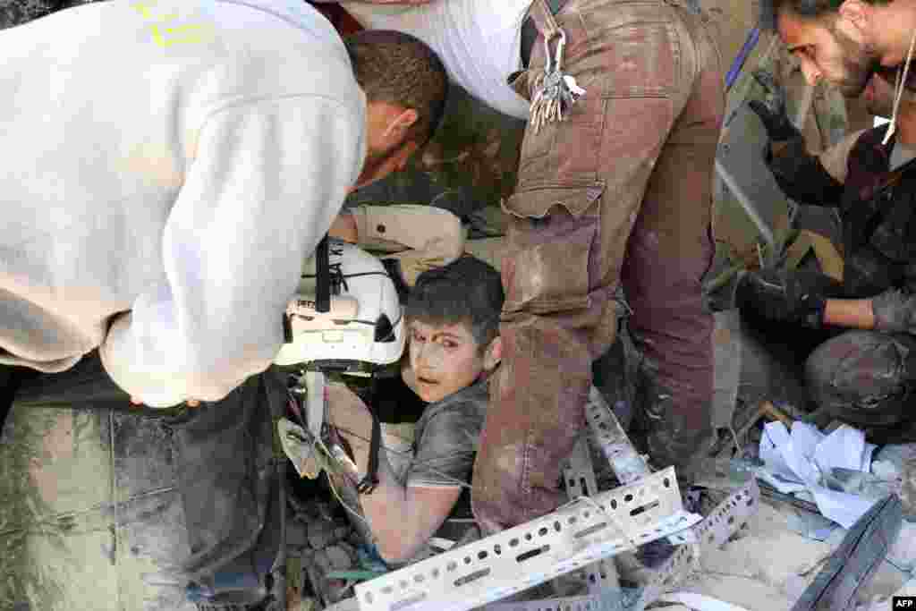 Para relawan Suriah menolong seorang anak yang terjepit di antara reruntuhan bangunan pasca serangan udara di distrik Tariq al-Bab, kota Aleppo, Suriah.