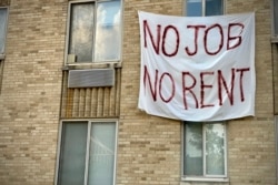 FILE - A banner against renters' evictions reading “No job, no rent” is seen on an exterior wall of an apartment building in Washington, D.C., August 09, 2020.