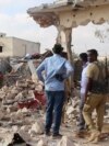 In this image taken from video on March 12, 2025, observers and security officers look over the aftermath of a car bomb explosion the previous day at a hotel in the central Somali city of Beledweyne.
