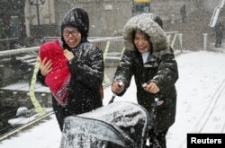 Two women make their way through snow in Canary Wharf, London, Britain, Feb. 27, 2018.