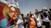 A supporter of Egypt's former President Hosni Mubarak holds a defaced picture of U.S. ambassador to Egypt Anne Patterson (bottom) and U.S. President Barack Obama (top) as others shout slogans against members of the Muslim Brotherhood and supporters of ousted Egyptian President Mohamed Morsi, before Mubarak's trial in Cairo, July 6, 2013. 