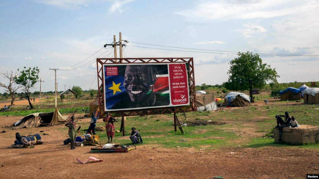 Civilians preparing to flee from renewed attacks gather in front of a sign celebrating the second anniversary of South Sudan's independence in Bentiu, Unity state of South Sudan, April 20, 2014.