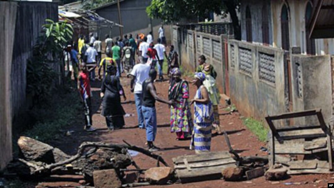 Residents of the mostly Peul suburb of Bambeto, Conakry, walk back to their homes behind barricades they set after a shooting incident, 17 Nov 2010