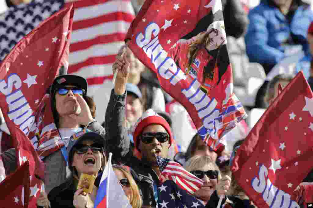 Fans wave flags for United States skier Julia Mancuso during the downhill portion of the women's supercombined, Krasnaya Polyana, Feb. 10, 2014.