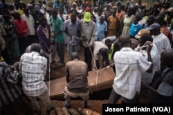 The casket containing the body of Duku Evans, who was killed November 3 amid fighting between government troops and rebels in Logo displaced persons camp in Kajo Keji, South Sudan, is lowered into a grave on the Ugandan border, Nov. 5, 2017.