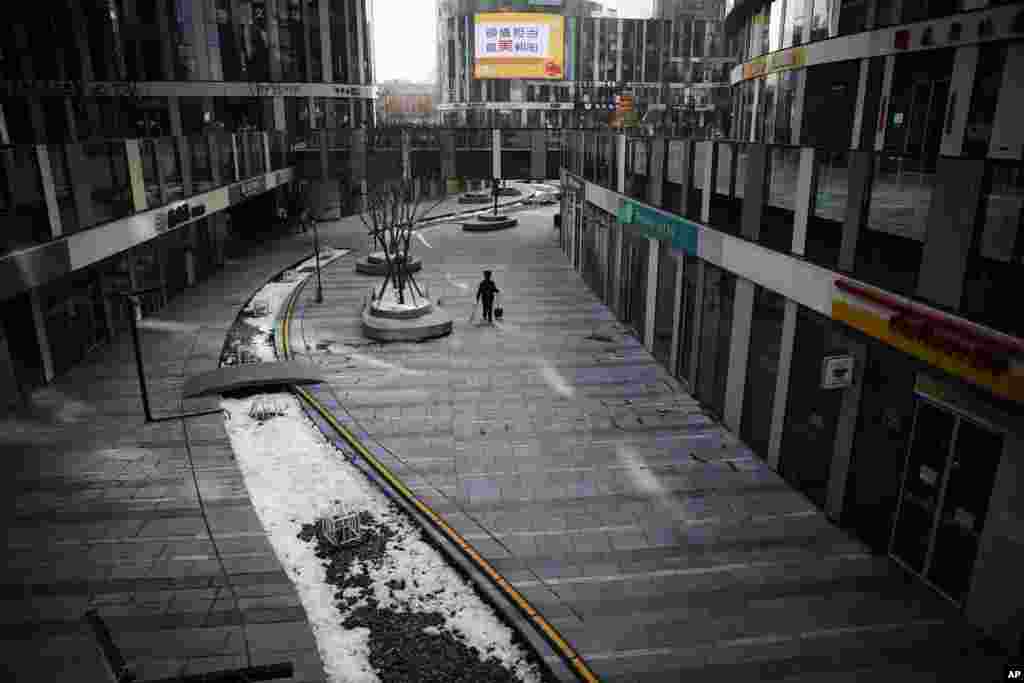 A cleaner walks through a deserted compound of a commercial office building in Beijing, China. China reported a rise in new virus cases, possibly denting optimism that its disease control measures like isolating major cities might be working.