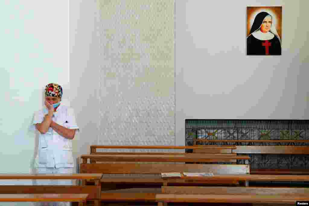 A medical staff member is seen inside the chapel in the San Giovanni hospital before the chaplains bring a cross outside to give a blessing to the medical staff on Good Friday, as Italy is under lockdown to try to stop the spread of the coronavirus diseas