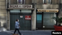 FILE - A person walks a dog past a closed shop during the second national lockdown as part of the measures to fight a second wave of the coronavirus disease in Nice, France, Nov. 17, 2020.