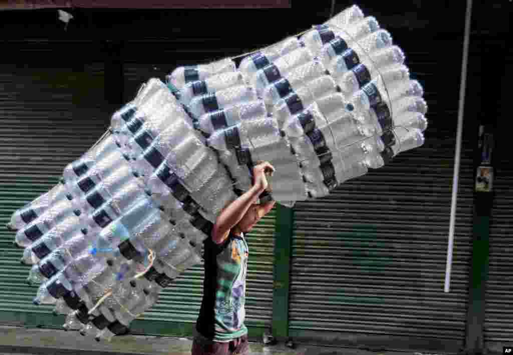 Seorang anak Bangladesh membawa botol-botol plastik kosong di jalan di Dhaka.