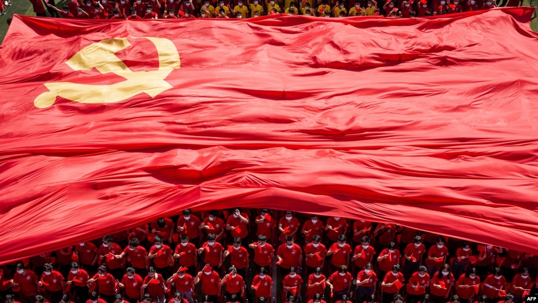 FILE - University students display the flag of the Communist Party of China to mark the party's 100th anniversary, in Wuhan in China's central Hubei, Sept. 10, 2021.