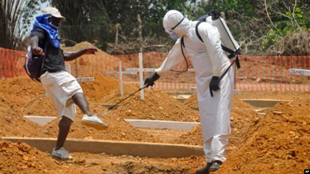 FILE - A man is sprayed with disinfectant after he celebrated the memory of a loved one who died due to the Ebola virus at a newly build grave yard for Ebola virus victims in Monrovia, Liberia, March 11, 2015. 