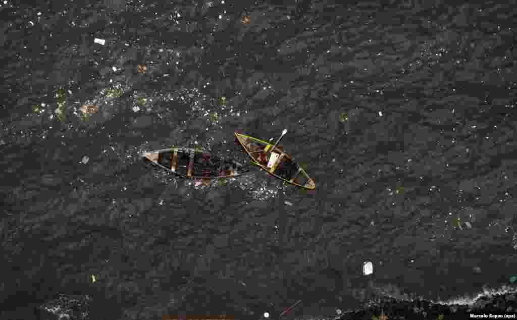 Dua nelayan tampak mencari ikan di Teluk Guanabara yang penuh dengan polusi, di mana lomba layar Olimpiade akan diadakan di Rio de Janeiro, Brazil.