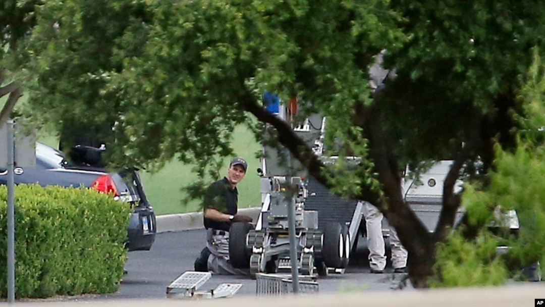 FILE - Police appear to set up a remotely operated robot during a stand-off with a gunman barricaded inside a van at a Jack in the Box restaurant in Hutchins, Texas. 