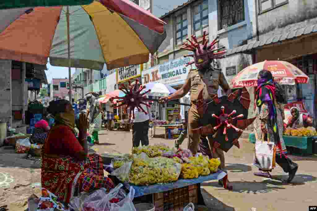 A policeman wearing a coronavirus-themed outfit, gestures towards a vendor at a market to raise awareness about social distancing, during a nationwide lockdown in Chennai, India.
