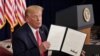 El presidente Donald Trump muestra a las cámaras una de las órdenes ejecutivas para asistencia federal por el coronavirus firmadas el sábado 8 de agosto de 2020.