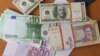 FILE - The euro and United States $100 bill are seen next to Iran's rial.