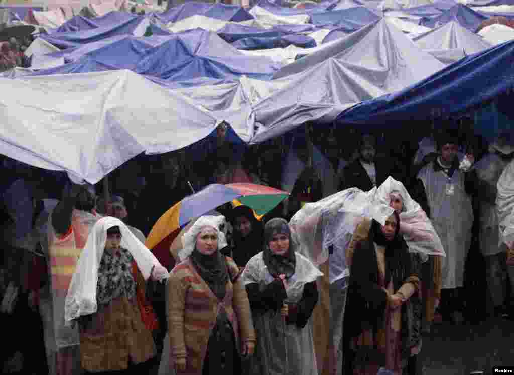 Supporters of Tahir-ul Qadri listen to him while standing in the rain during the fourth day of protest in Islamabad, Pakistan, January 17, 2013.