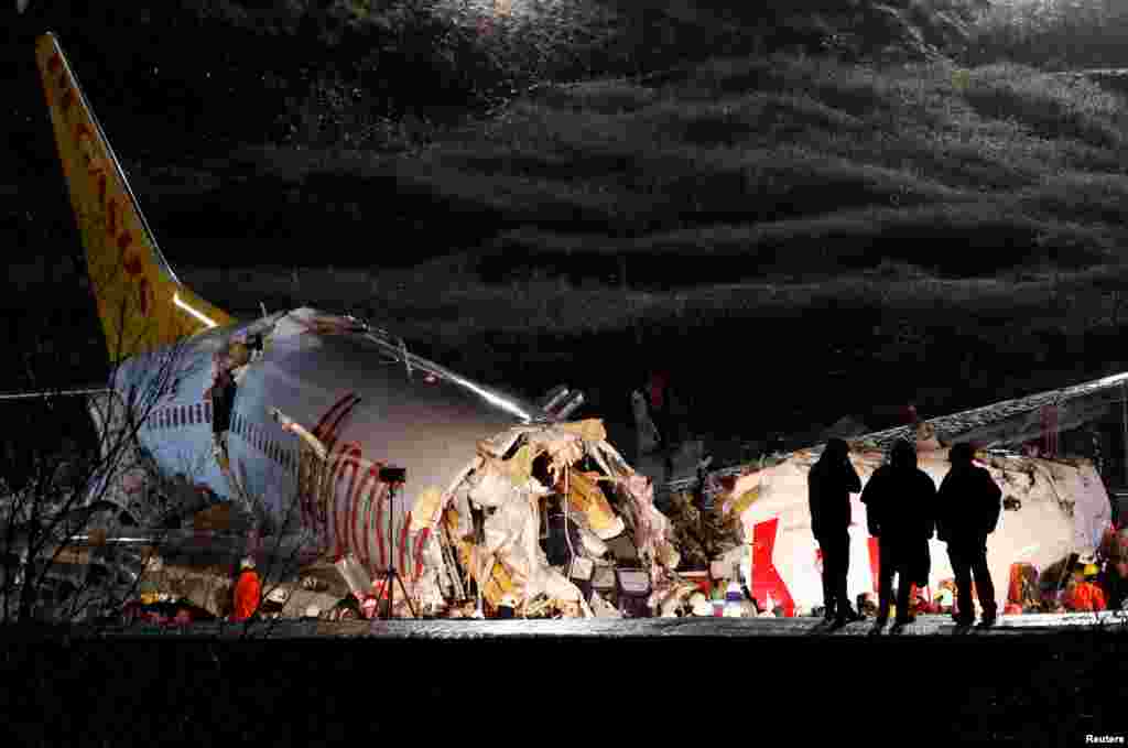 Police officers inspect the Pegasus Airlines Boeing 737-86J plane, that overran the runway during landing and crashed, at Istanbul's Sabiha Gokcen airport, Turkey.