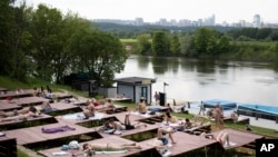 People rest at a one of parks by the Moscow River during a hot day in Moscow, Russia, June 9, 2020. 