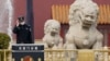 一名中國警察站在北京天安門前的石獅子旁。（2021年3月11日）
